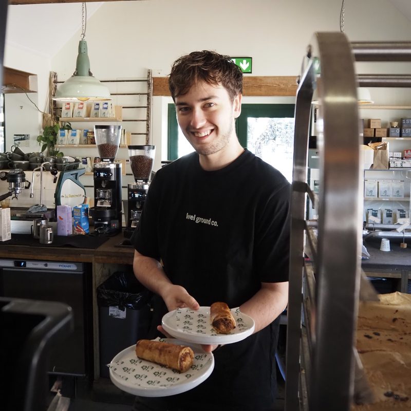 Smiling team member serving pastries on plates in the café