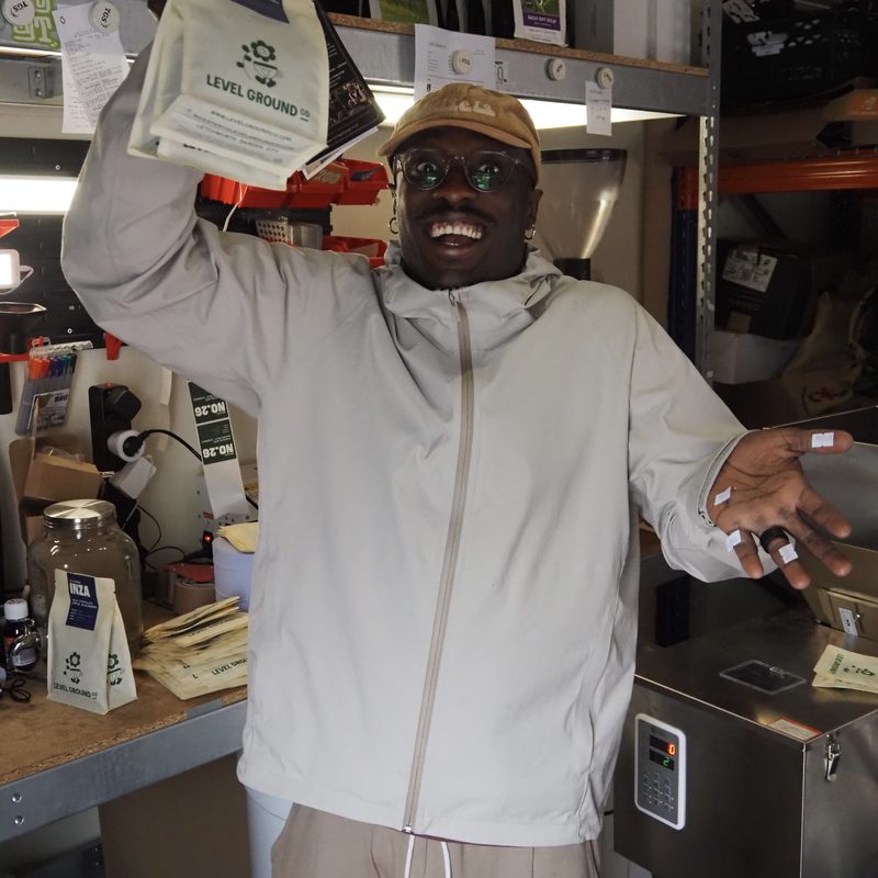 Team member cheering with a bag of Level Ground coffee in the roastery
