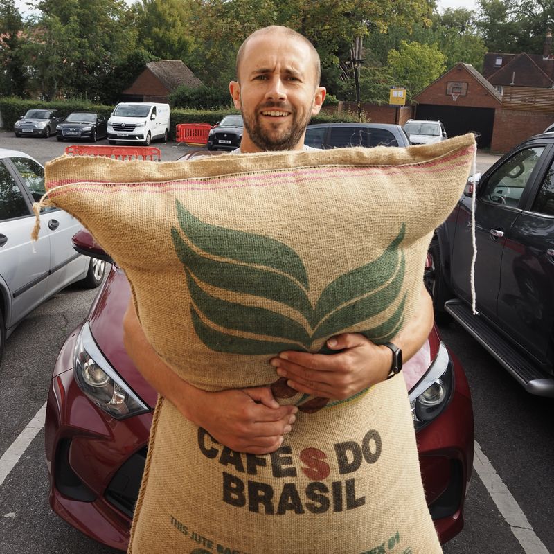 Team member hugging a large sack of Brazilian green coffee beans
