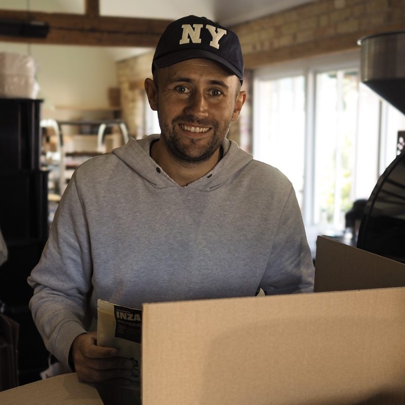 Smiling team member in a cap packing a box