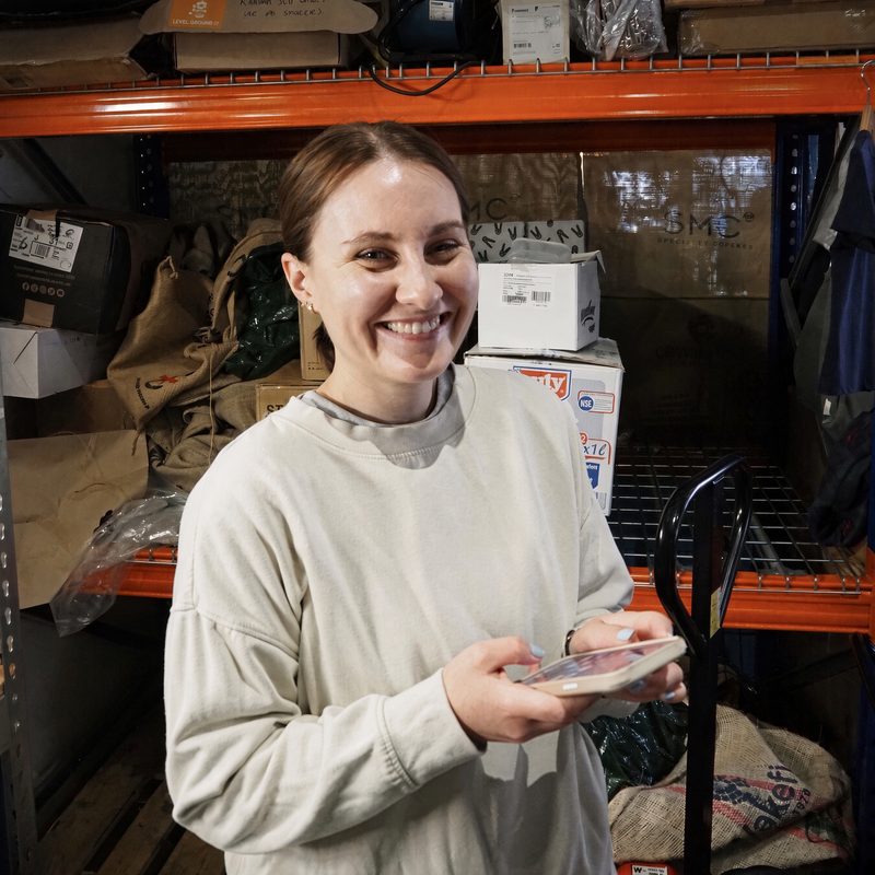 Smiling team member holding a phone in the stockroom